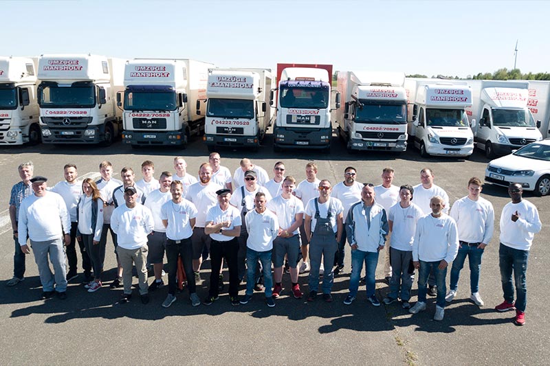 Das Team von Umzüge Mansholt vor Umzugs-Lkw, Transportern und Autos