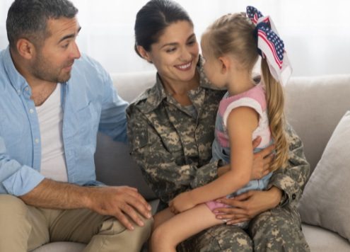 Eine Soldatin mit Mann und Kind sitzt auf einem Sofa