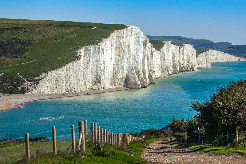 Blick auf die White Cliffs of Dover vor strahlend blauem Wasser.