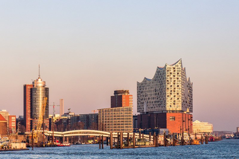 Blick auf das Hamburger Hafenbecken mit der dominanten Philharmonie im rötlichen Licht der untergehenden Sonne
