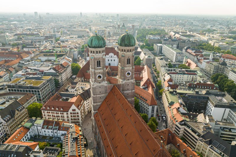 Luftaufnahme von München mit Blick auf die Frauenkirche und das Voralpenland