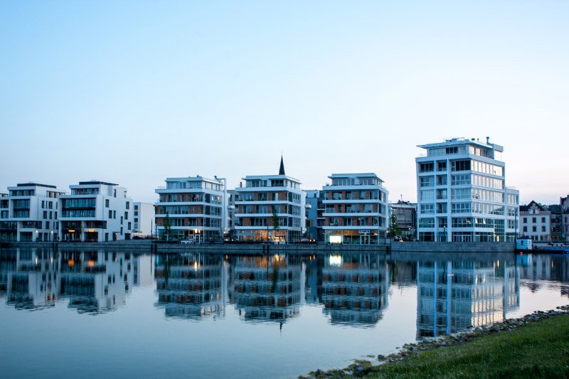 Moderne Wohngebäude am Wasser mit Spiegelungen im ruhigen See bei Abendlicht in Dortmund.