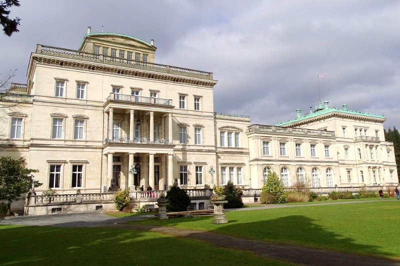 Historistische „Villa Hügel“ in Essen mit Säulenportikus und weitläufigem Rasen im Vordergrund unter bewölktem Himmel