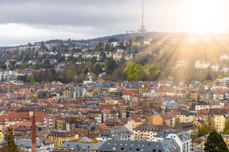 Stuttgarter Stadtpanorama mit dicht bebauten Wohnvierteln und dem Fernsehturm auf dem Hügel im Sonnenlicht