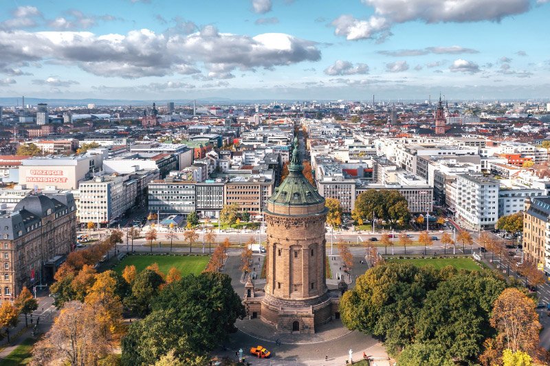 Panoramablick über Mannheim mit dem Wasserturm im Vordergrund, der Innenstadt und den charakteristischen Quadraten unter blauem Himmel